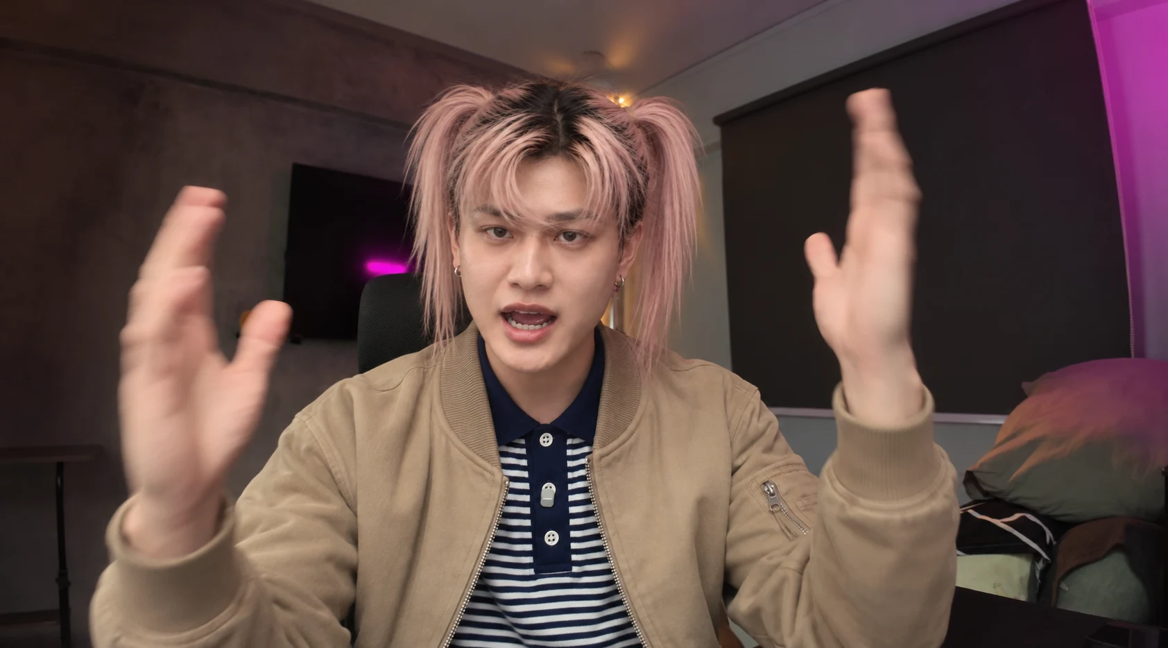 Adult character with pink twin ponytails, a tan jacket and striped polo, raising both hands in the original room.